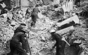 People looking through rubble in the aftermath of a bomb during WWII